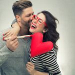 Lachendes Paar mit Herzsymbol | Verlobungsringe