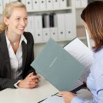 Frau im Bewerbungsgespräch mit Mappe | Tattooentfernung Essen
