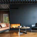 Edler Wohnraum mit klaren Linien, gemuetlicher Feuerstelle und hochwertigen Materialien als atmosphaerischer Rahmen fuer einen Specksteinofen.